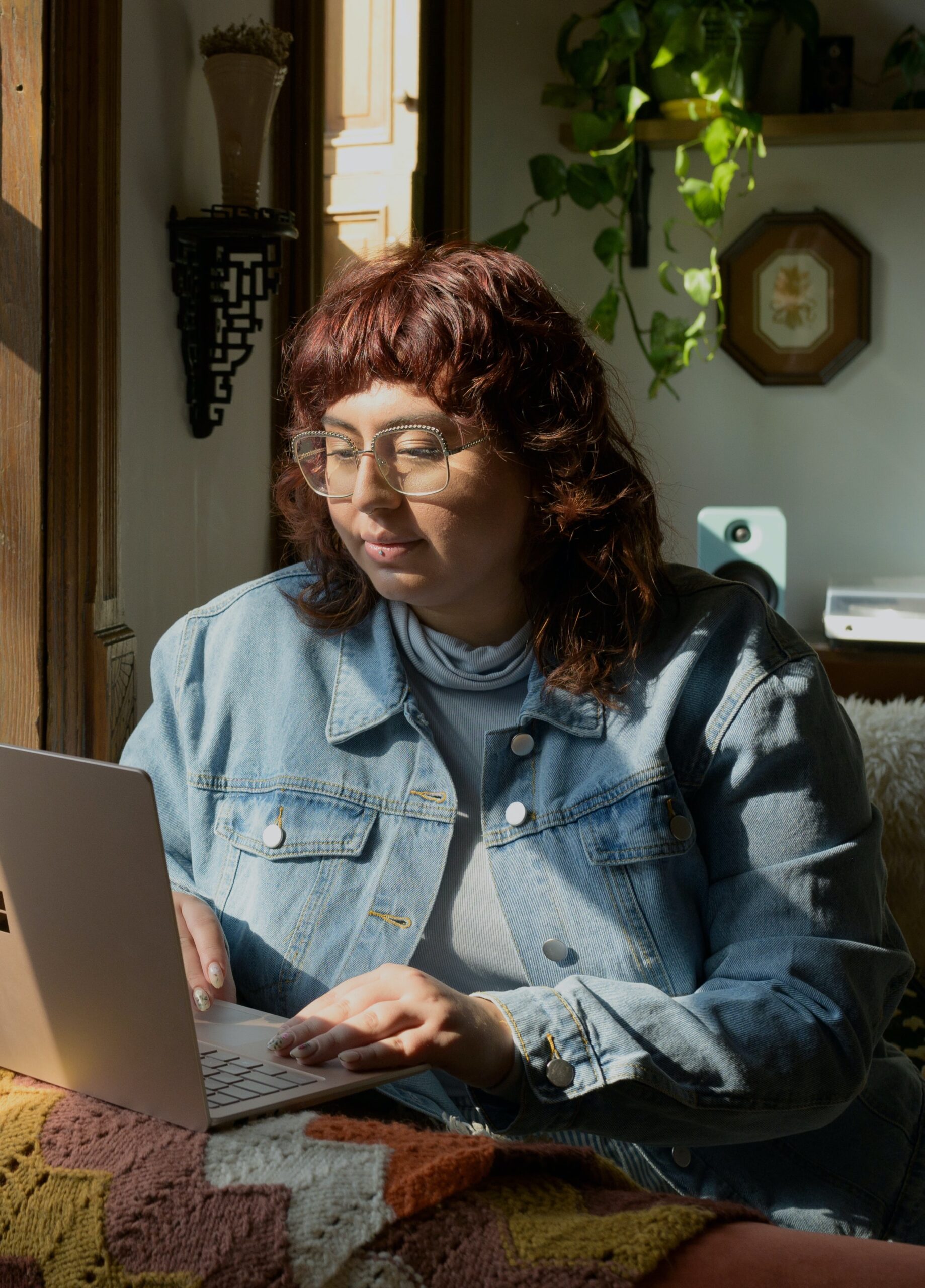 Person sitting next to a window, on a laptop, registering for the Exploring Your Body Story: Online Retreat.