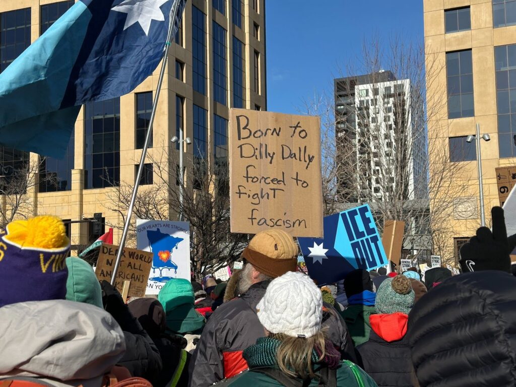 Photo of MN protestor with sign reading: Born to dilly dally, forced to fight facism.